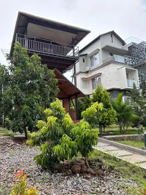 a tree in front of a house with a building at Coorg Riverness Resort in Kushālnagar