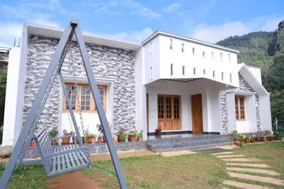 a white house with a swing in front of it at Munnar Mountain view cottage in Munnar