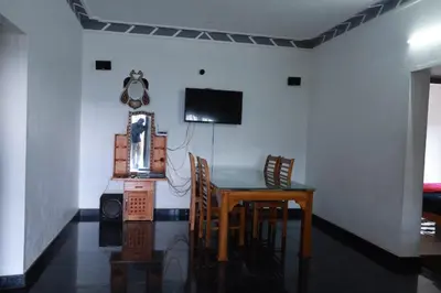 a dining room table with chairs and a television on a wall at Munnar Mountain view cottage in Munnar