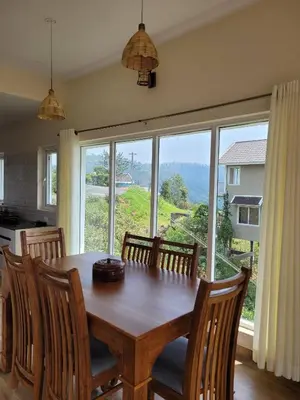 a dining room table with chairs and a large window at The Ark Haven Ooty by Scenic Serenity Stays in Ketti