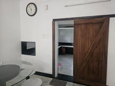 a door leading into a room with a table and a clock at Shiva Shambo Home Stay - Entire Villa in Coimbatore