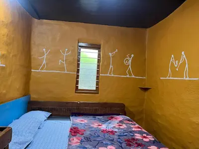 a bedroom with a bed and a window with drawings on the wall at Kovilakam in Vattavada