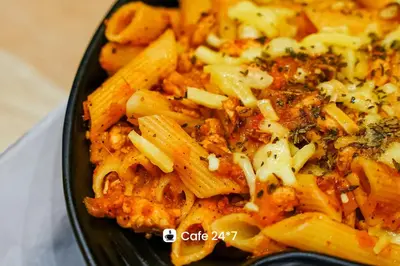 a black plate of pasta with cheese and herbs at Dubai Frame Residency And Hotel in Thottada