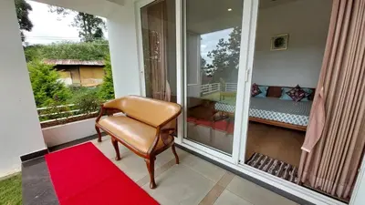 a porch with a chair and a bed on a balcony at Mayfield Valley Homestay in Kotagiri