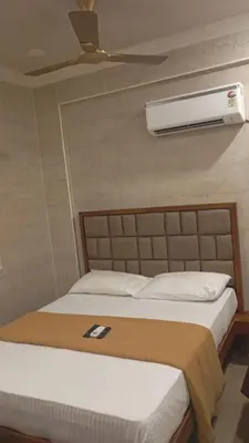 a bedroom with a bed with a air conditioner on the wall at Hotel Maharajas in Kāmānayakkanpālaiyam