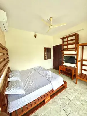 a bedroom with a large bed and a table at GroveStay in Chakkarakkal