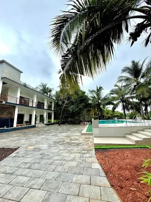 a courtyard with a building and a palm tree at GroveStay in Chakkarakkal