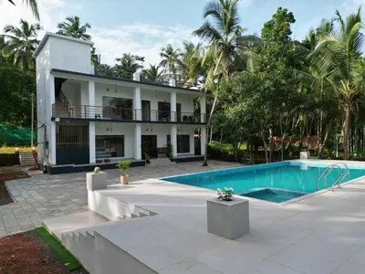 a house with a swimming pool in front of it at GroveStay in Chakkarakkal