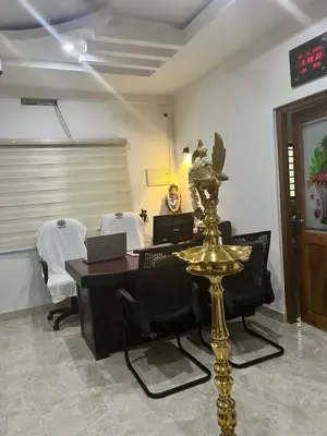 a room with a desk and chairs and a table with a laptop at SREE CHAKRA Tourist Home Guruvayoor in Guruvāyūr