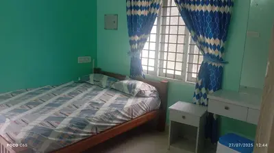 a bedroom with a bed with blue walls and a window at Mannath Home Stay in Alwaye