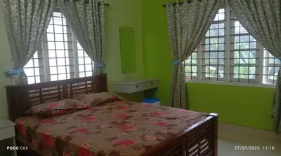 a bedroom with a bed and two windows at Mannath Home Stay in Alwaye