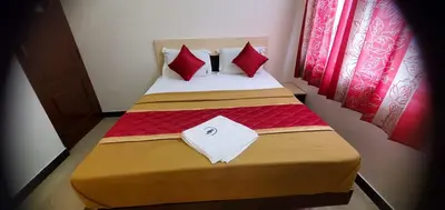 a bedroom with a bed with red pillows at Hotel BMR Stay in Pollāchi