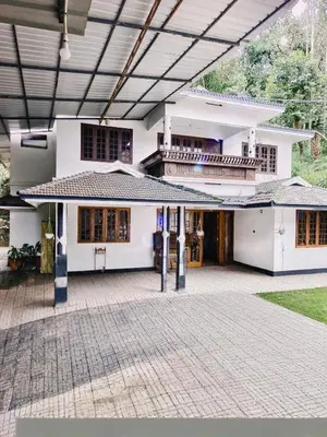 a large white house with a large patio at Banasura Green paradise , Villa , Deluxe rooms , Budget rooms in Padinjarathara