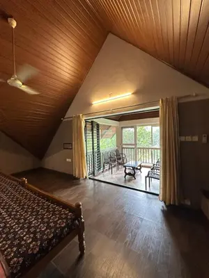 a living room with a bed and a balcony at Cottage on Riverside in Irinjālakuda