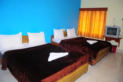 two beds in a hotel room with a tv at Hotel Zaraa in Ooty