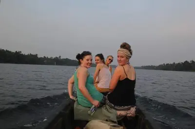 three women standing in a boat on the water at Pearl Spot in Alwaye
