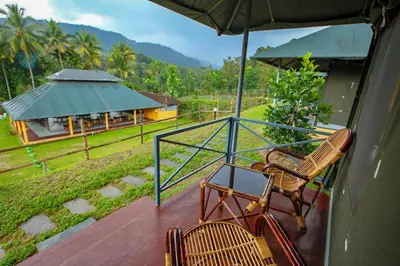 a balcony with two chairs and an umbrella at Nature's nest in Kuttampuzha
