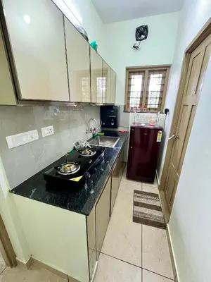 a kitchen with a counter and a sink and a refrigerator at Ayat Apartments - near to Rajagiri Hospital in Alwaye