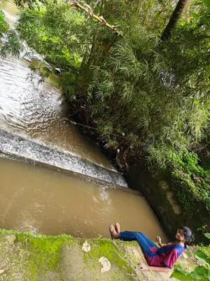 a woman laying on the ground next to a river at Full Home Wayanad Bathery in Sultan Bathery