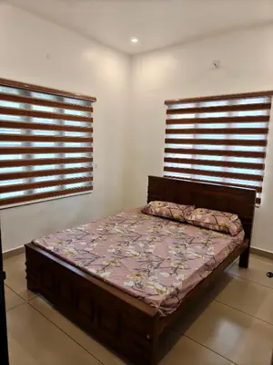 a bed in a room with two windows at Full Home Wayanad Bathery in Sultan Bathery