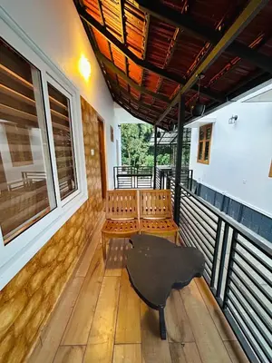 a balcony with chairs and a table and a ceiling at Vayalil Homestay in Karuvārakundu