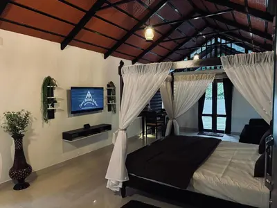 a bedroom with a bed with curtains and a tv at Coorg Robusta Retreat in Suntikoppa
