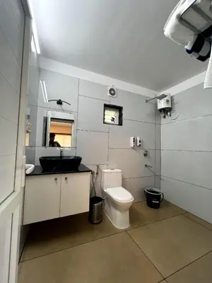 a bathroom with a toilet and a sink and a mirror at Pakalakam Resorts in Cheruppulasseri