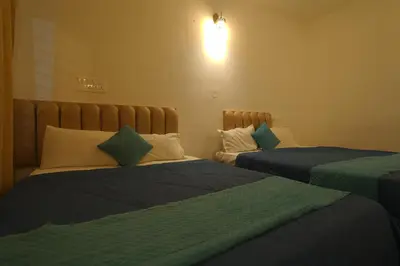 a bedroom with two beds with blue and white pillows at Cozy retreat in Mysore