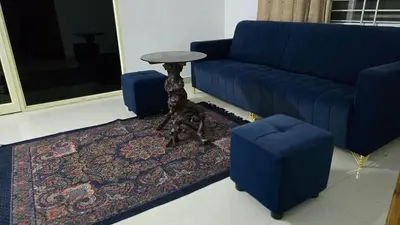 a living room with a blue couch and a table at Cozy retreat in Mysore