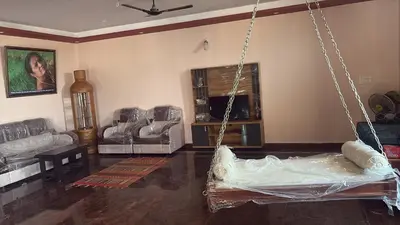 a living room with a hanging bed and chairs at Lakshminarayanappa Niwasa in Channapatna