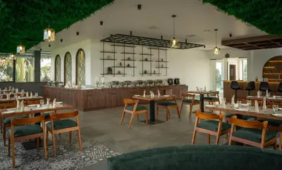 a restaurant with wooden tables and chairs and a kitchen at Boulevard Premium Luxury Hotel in Munnar
