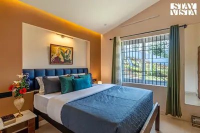 a bedroom with a blue bed and a window at StayVista at Rustling Pine with Bonfire, BBQ & Lawn in Ooty