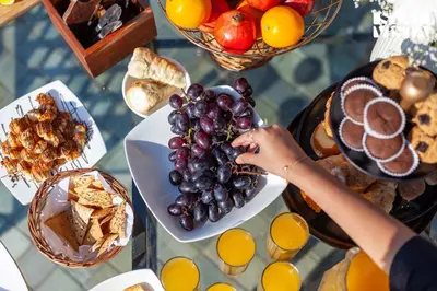 a person reaching for grapes on a plate of food at StayVista at Rustling Pine with Bonfire, BBQ & Lawn in Ooty