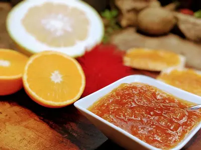 a bowl of jam and orange slices on a table at Tranquil Resort - Blusalzz Collection, Wayanad - Kerala in Ambalavayal