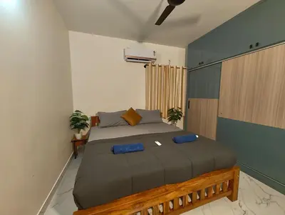 a bedroom with a large bed with blue pillows at Luxurious 3BHK AC, Peaceful location, Premium stay in Mysore