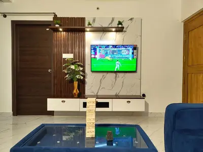 a living room with a tv on a wall at Luxurious 3BHK AC, Peaceful location, Premium stay in Mysore
