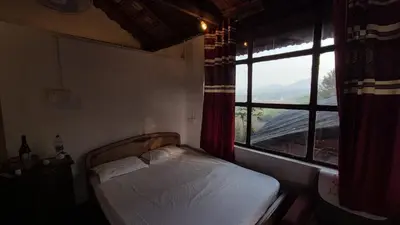 a small bedroom with a bed and a window at Tribal land homestay in Kushālnagar