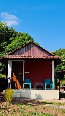 a small red house with blue chairs in front of it at Jungle Homes in Kollengode