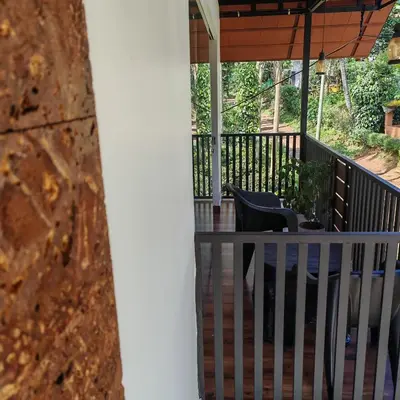a porch with a railing and chairs on it at Heaven Crest Holidays and Plantations in Chithragiri