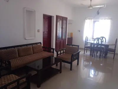 a living room with a couch and a table and chairs at Ocean blue home stay in Pallipuram