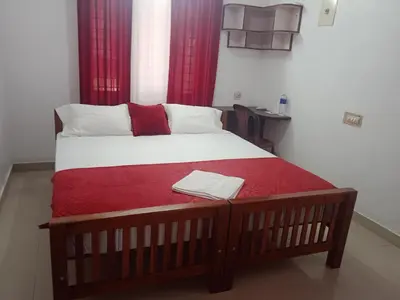 a bed in a room with a red blanket on it at Ocean blue home stay in Pallipuram