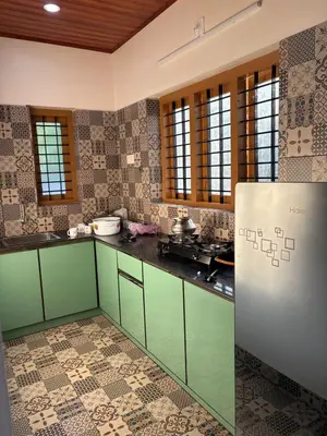 a kitchen with green cabinets and tile floors at Keshavam Homestay in Guruvāyūr