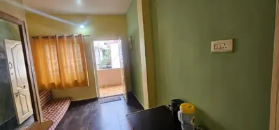 a room with green walls and a table and a door at Stay Awhile Cottages in Ooty