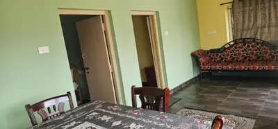 a dining room with a table and a couch at Stay Awhile Cottages in Ooty