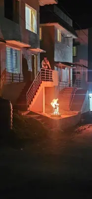 a fire in front of a house at night at Stay Awhile Cottages in Ooty