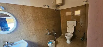 a bathroom with a toilet and a sink at Stay Awhile Cottages in Ooty