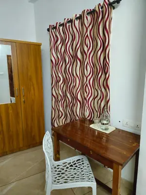 a room with a wooden table and a curtain at RF Tower in Kozhikode