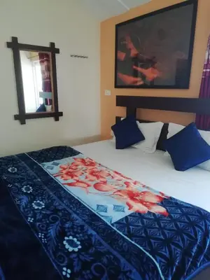 a bedroom with a large bed with a blue blanket at Queenhill Apartment in Ooty