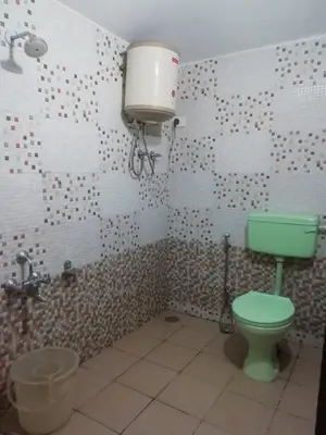 a bathroom with a green toilet and a sink at Queenhill Apartment in Ooty