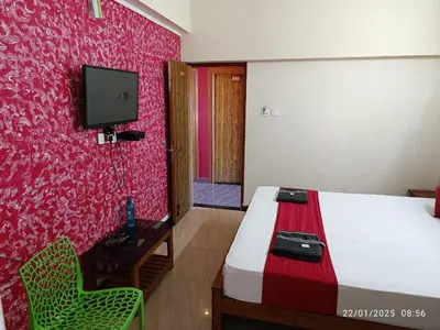 a bedroom with a bed and a tv on a wall at Queenhill Apartment in Ooty